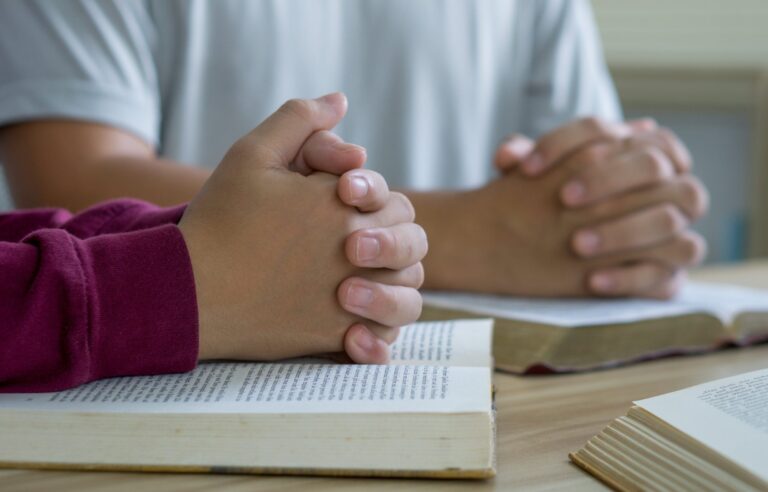Prayer meeting concept.Colleagues shaking hands reading scriptur